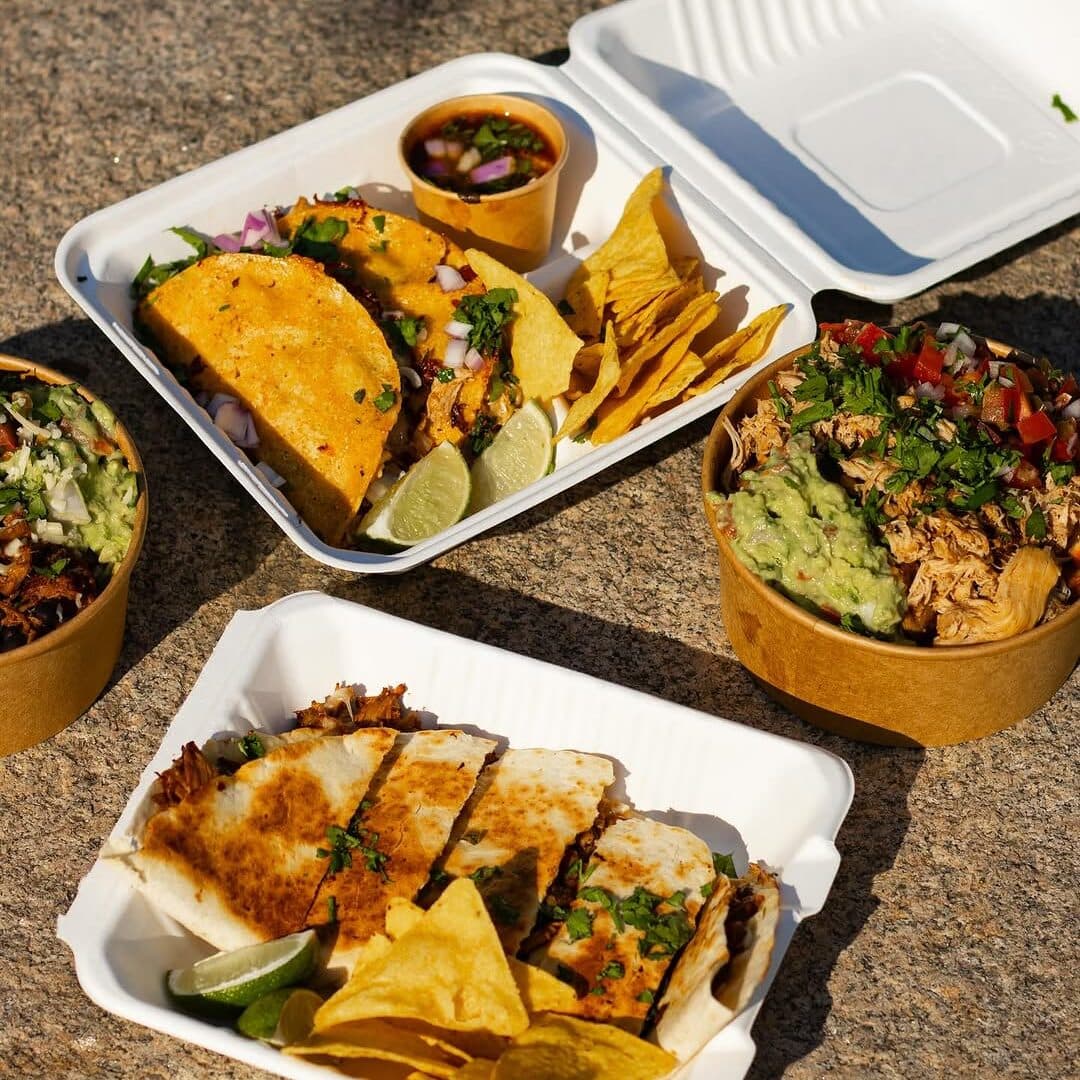 A spread of tacos, quesadillas and loaded bowls laid out in the sun