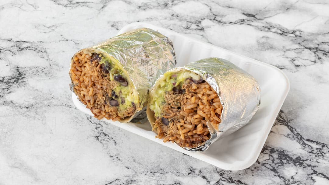 A flour tortilla burrito wrapped tight and sliced in half to show the filling