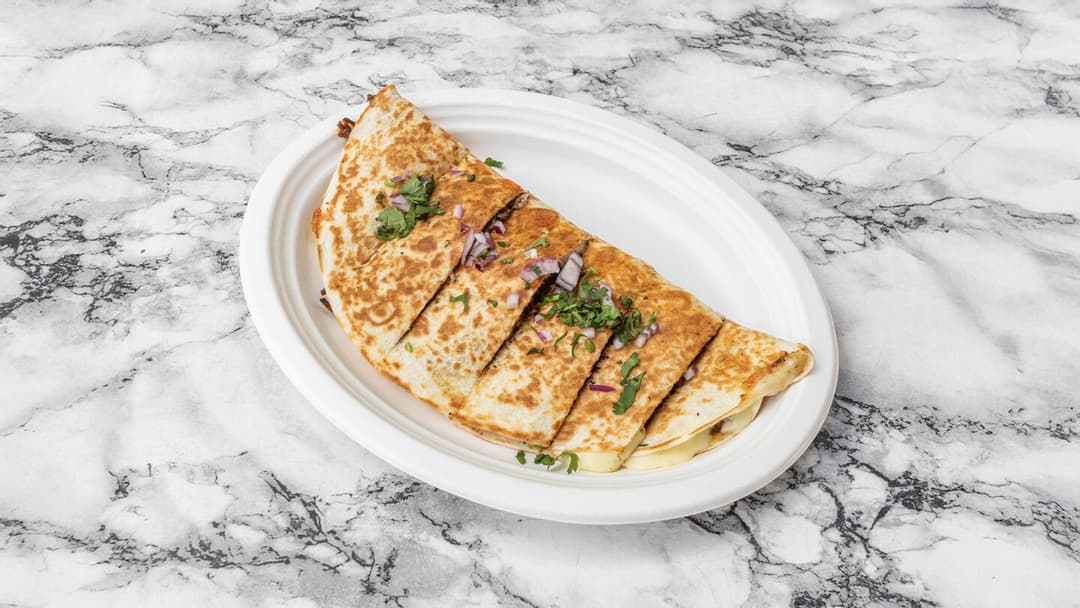 A grilled quesadilla cut into wedges, cheese stretching between the pieces